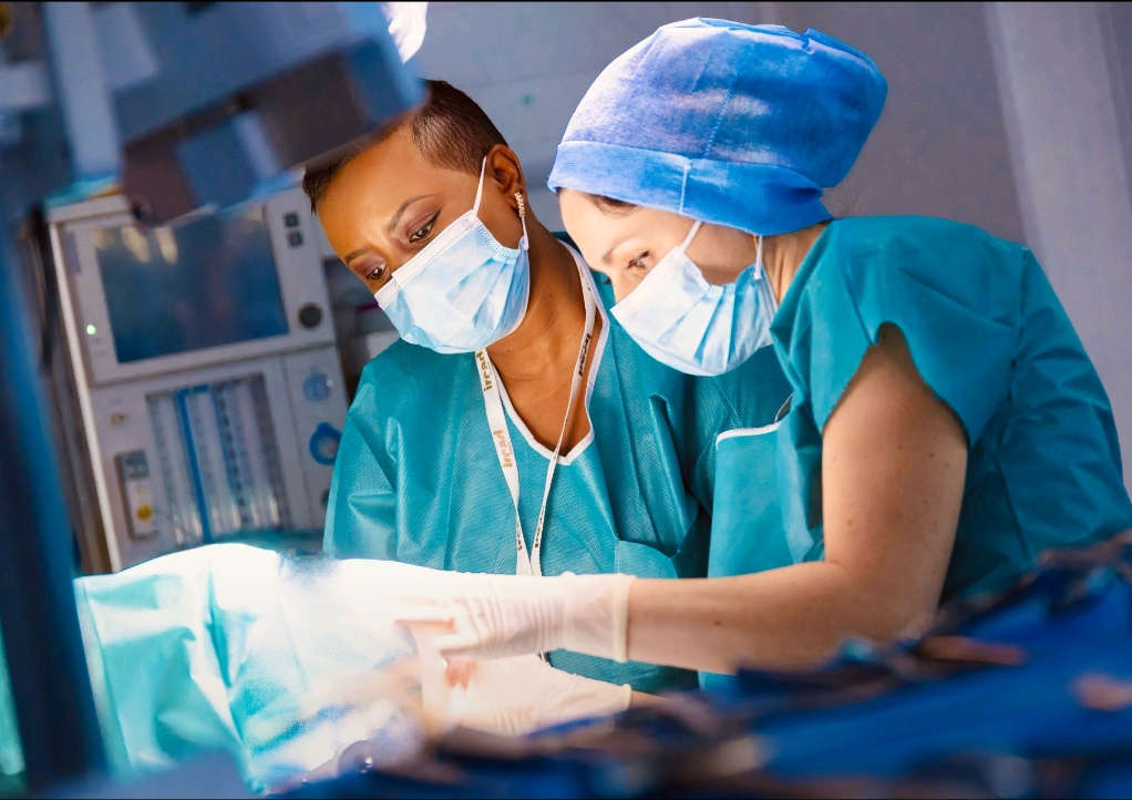 Mladi zdravniki pri asistiranju posega na ožilju.